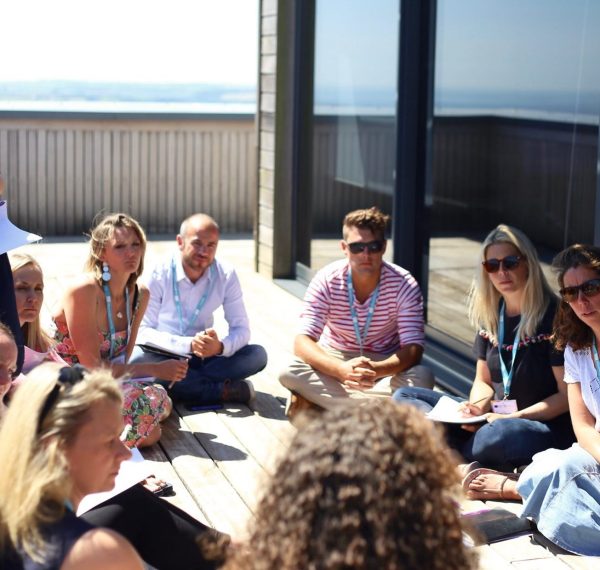 Mish is delivering a Retail course in the sunshine on a balcony.